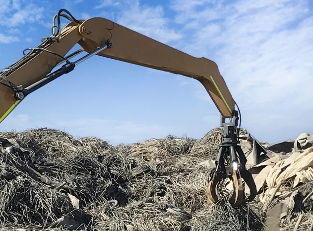 Excavadora con garra moviendo residuos industriales para su revalorización